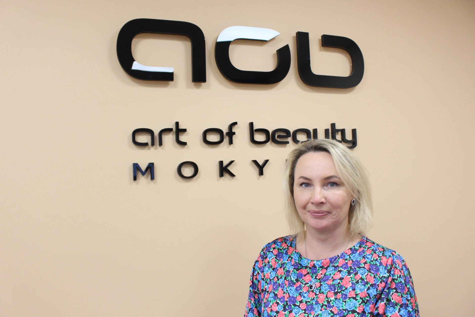Apskaitos dėstytoja Gitana Kulikovienė prie mokyklos „Art of Beauty“ logotipo