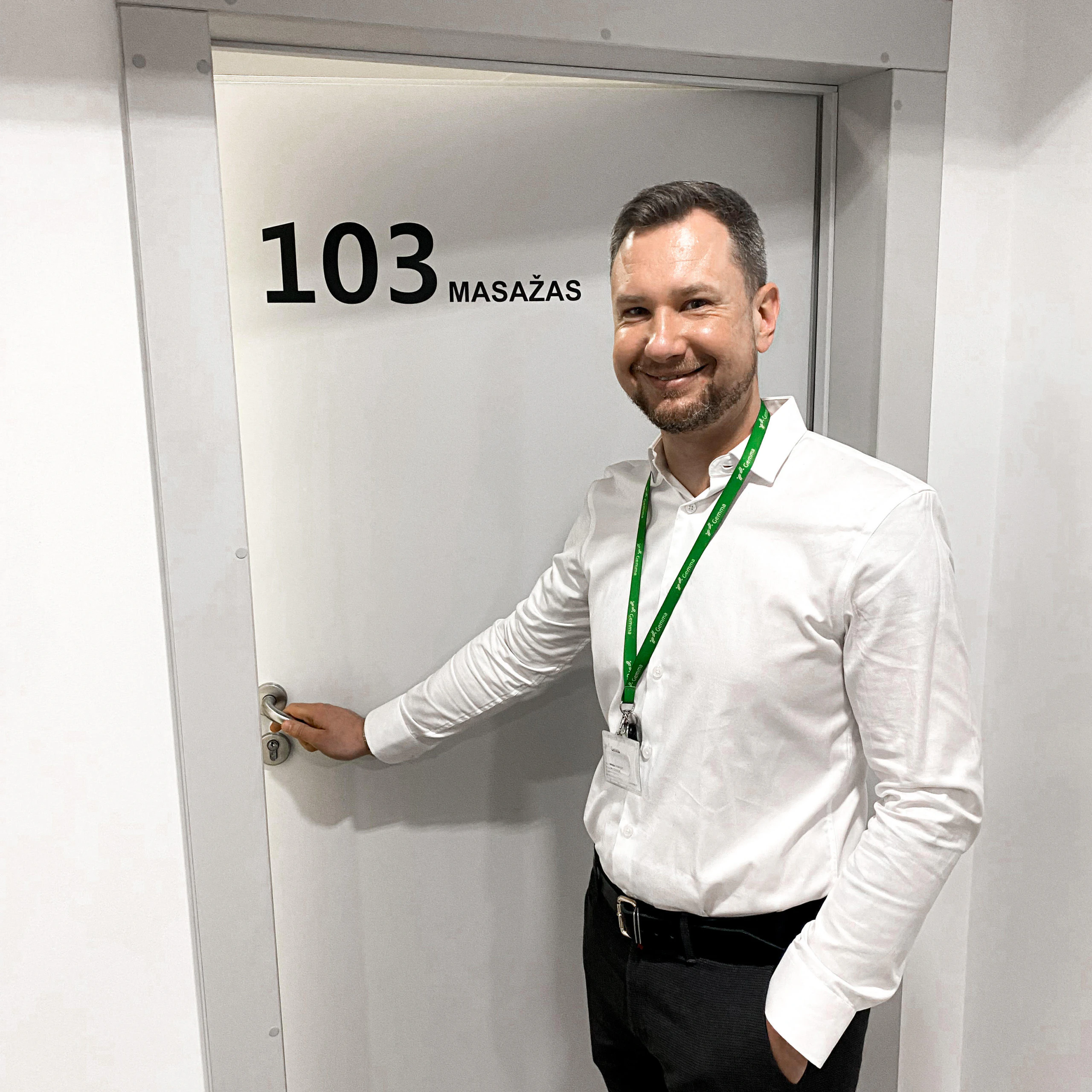 Masažuotojas Adomas prie masažo kabineto Nr. 103 durų