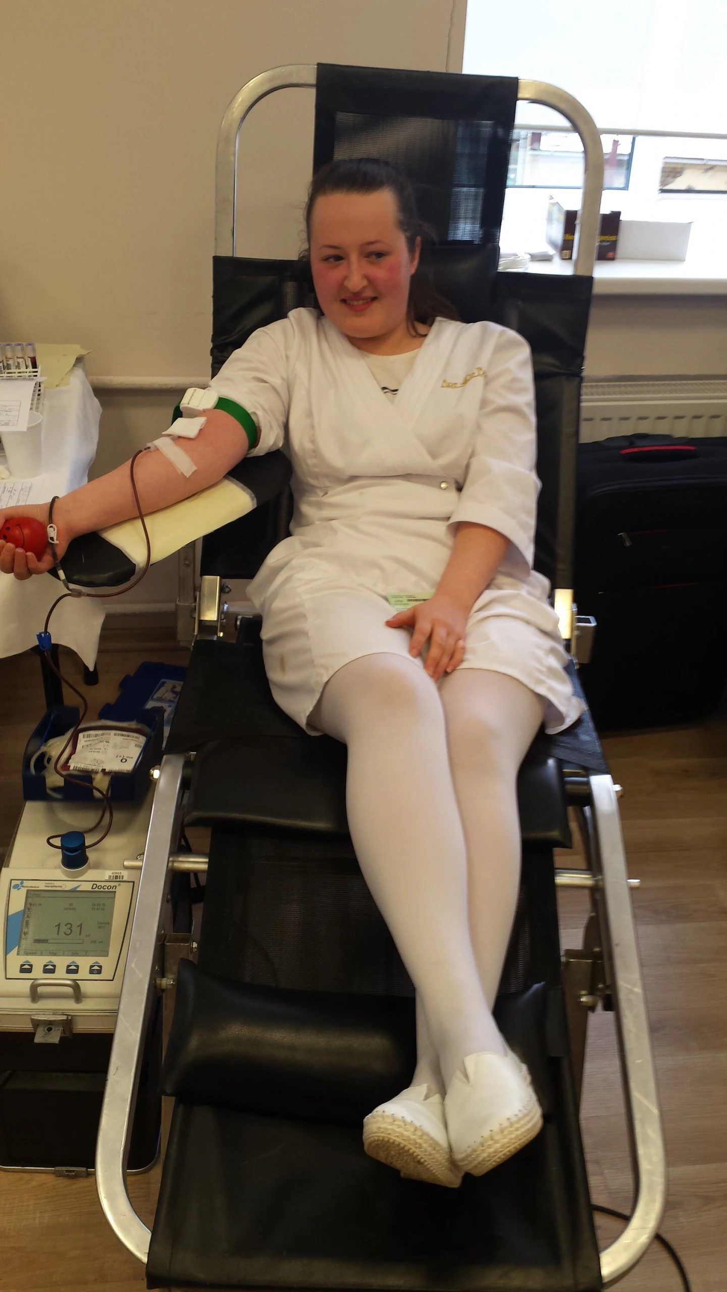 Donorė balta mokyklos uniforma aukoja kraują per donorystės akciją