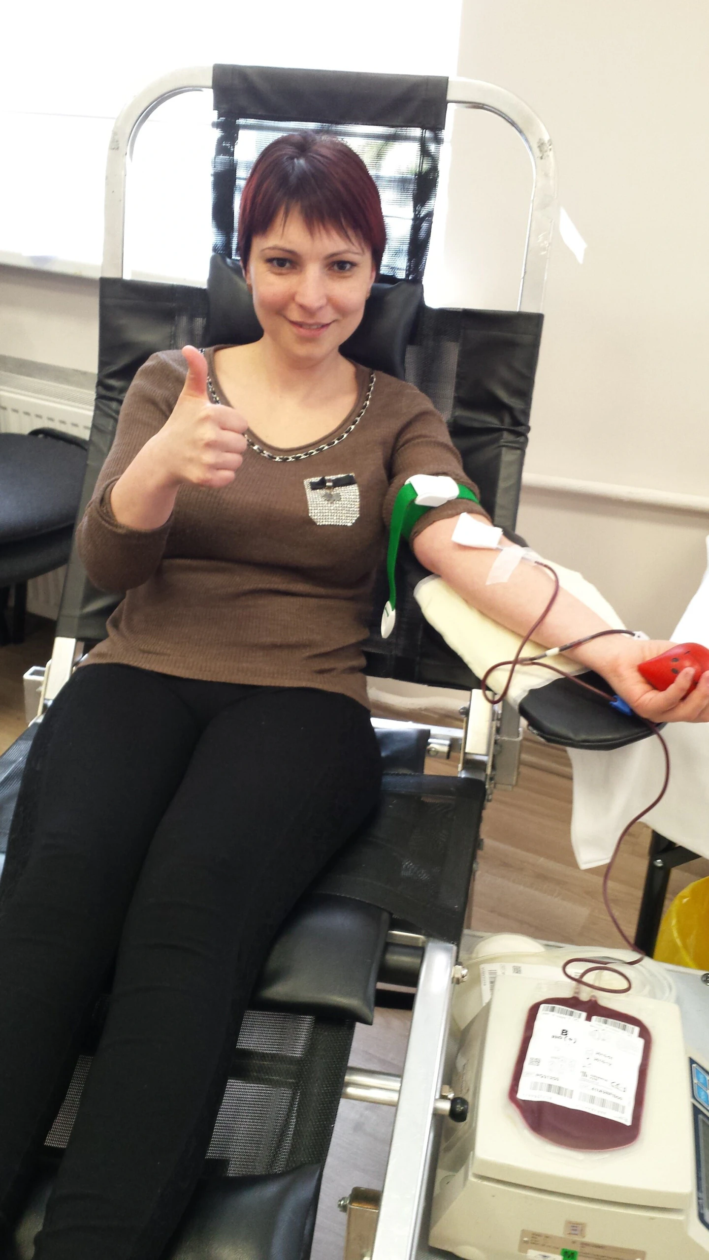 Donorė iškėlusi nykštį aukodama kraują per donorystės akciją