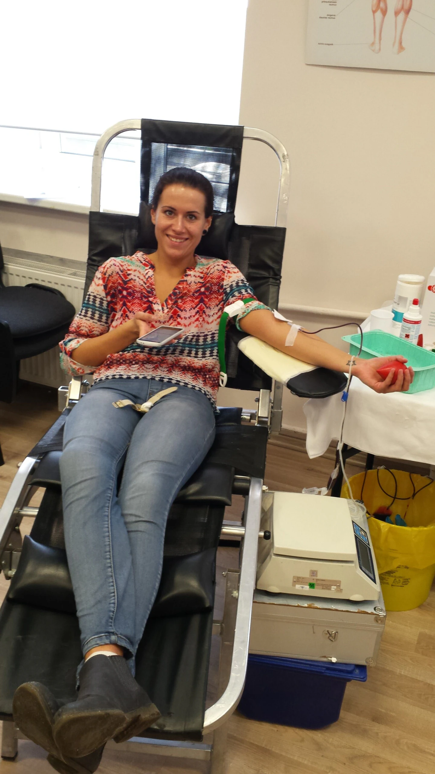 Donorė margaspalve palaidine šypsosi aukodama kraują