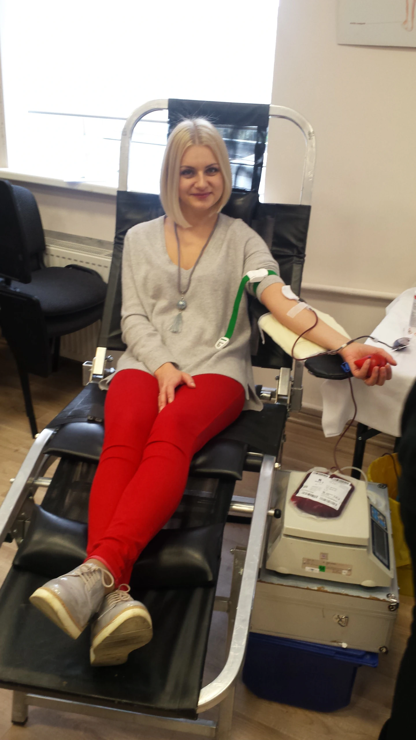 Donorė raudonomis kelnėmis aukoja kraują donoro kėdėje